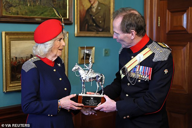 Colonel Richard Charrington presents Britain's Queen Camilla with a trophy which celebrates her visit to The Royal Lancers