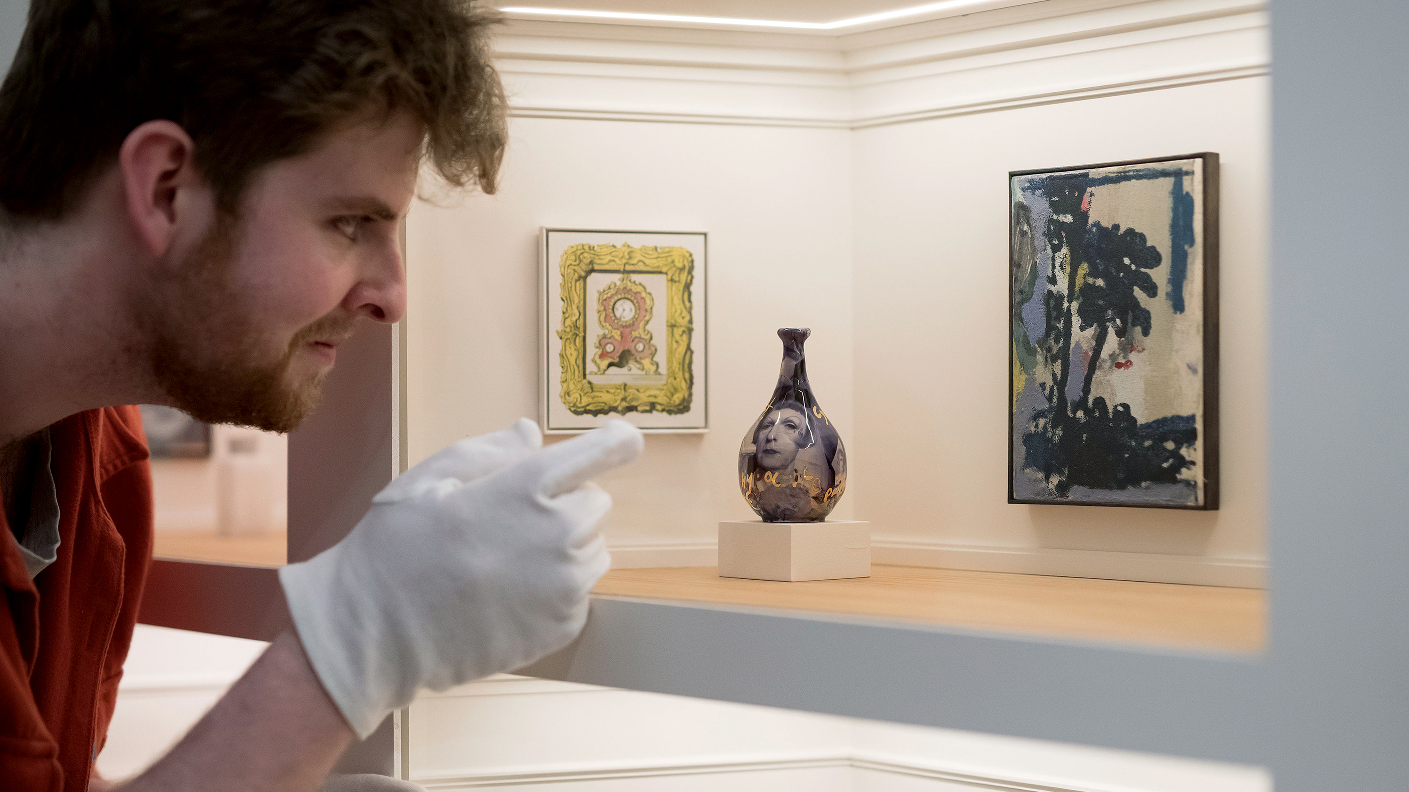 Ein Mann mit Handschuhen betrachtet eine Ausstellung in einer Modellkunstgalerie mit 80 originalen Miniaturkunstwerken