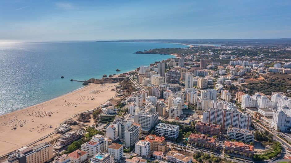 Luftaufnahme der Stadt Portimao über Wohngebäuden, Hochhäusern, am Strand Praia de Rocha mit Touristen.