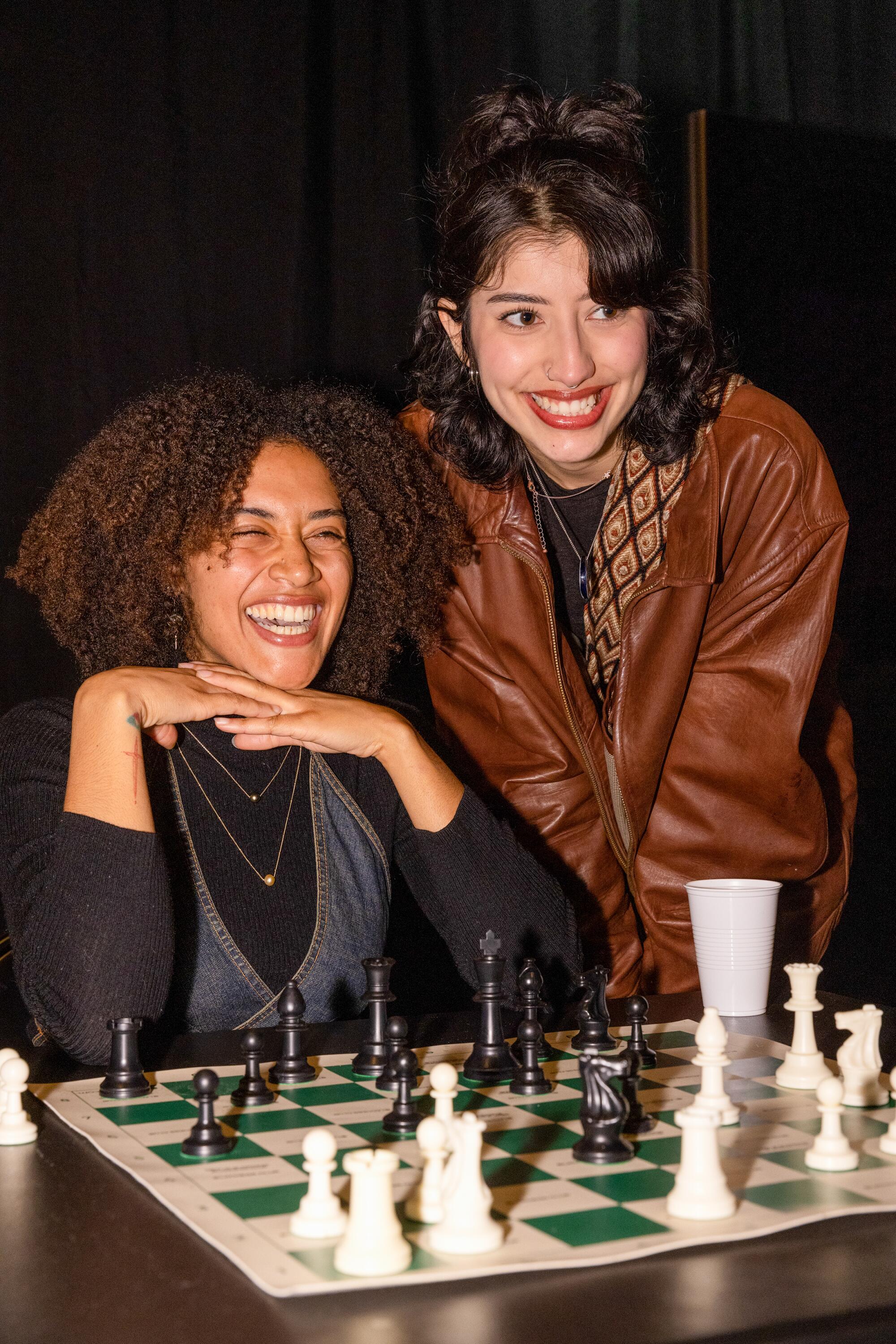 Zwei Personen spielen zusammen mit neuen Freunden eine Partie Schach.