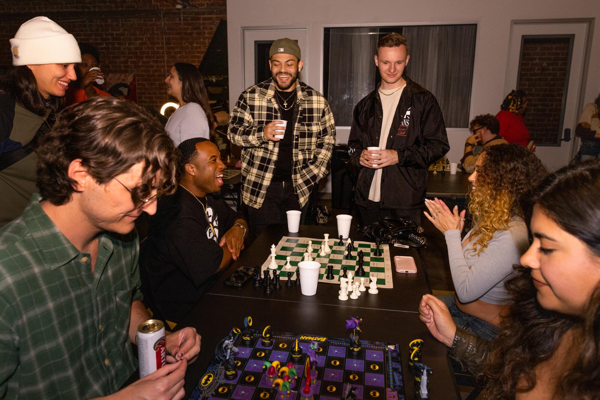 Eine Gruppe von Menschen, einige sitzend und einige stehend, spielen Schach und knüpfen Kontakte.