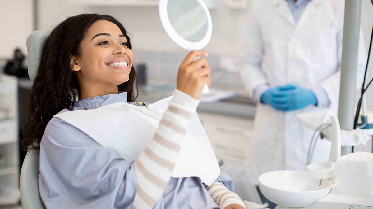 Frau untersucht ihre Zähne beim Zahnarzt