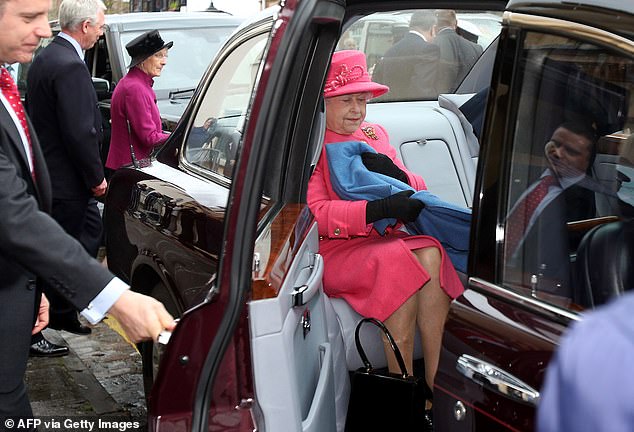 Königin Elizabeth scheint ihre Beine schnell mit einer Decke zu bedecken, als ihre Autotür geöffnet wird