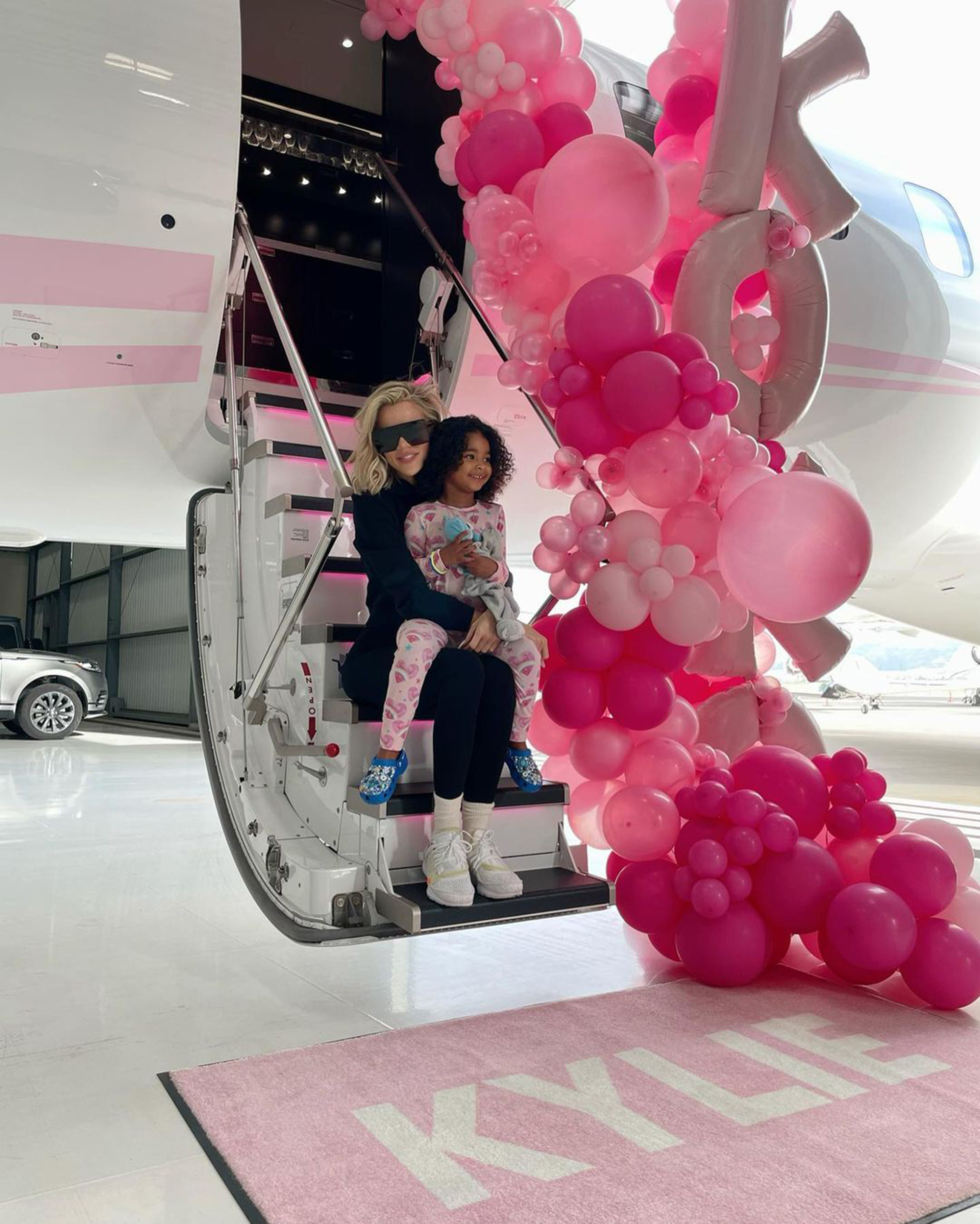 Khloé Kardashian und ihre Tochter True Thompson sitzen auf einer Flugzeugtreppe
