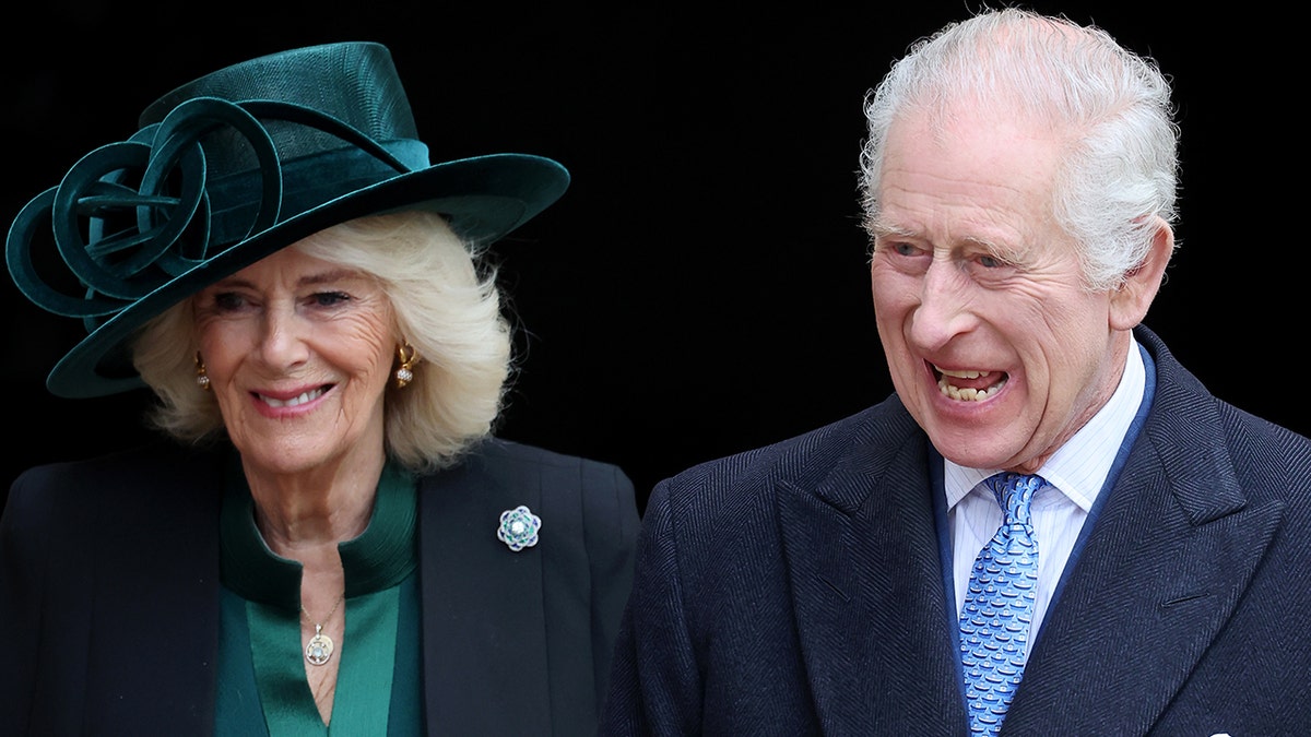 Königin Camilla in einer schwarzen Jacke und einer Queen-Bluse mit passendem grünen Zylinder lächelt sanft, als sie neben König Charles in einem schwarzen Anzug und einer blauen Krawatte geht und sehr fröhlich aussieht