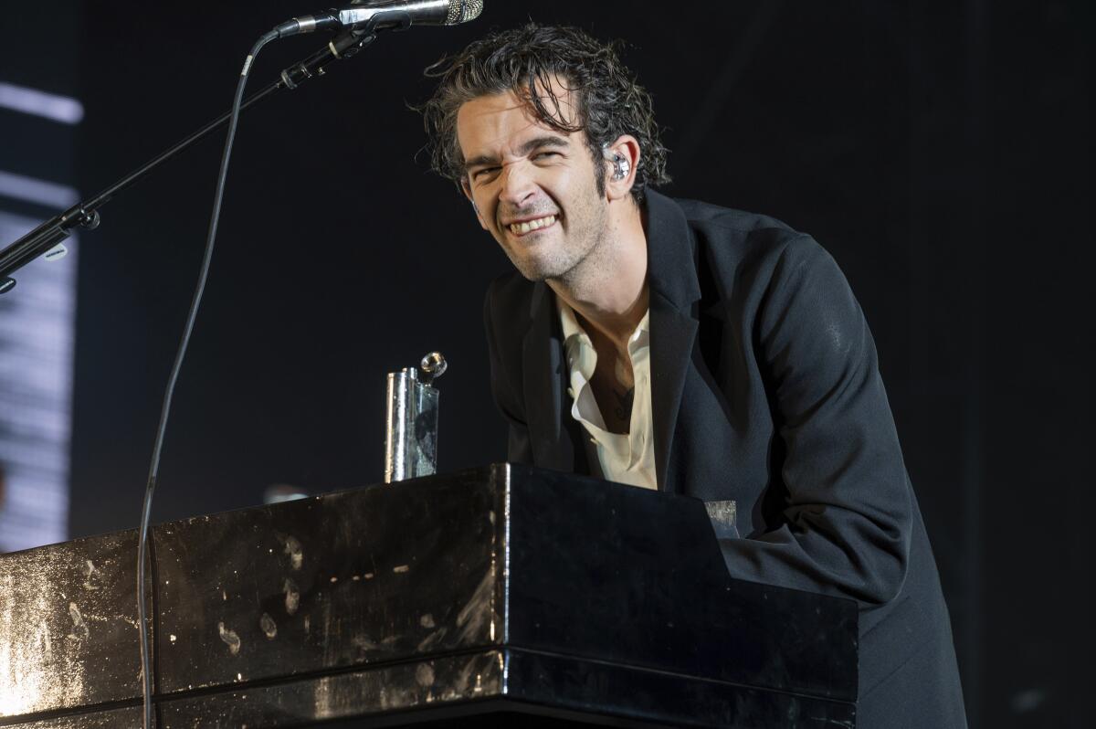Matty Healy spielt bei einem Konzert Keyboard, trägt eine schwarze Jacke und hat einen lustigen Gesichtsausdruck