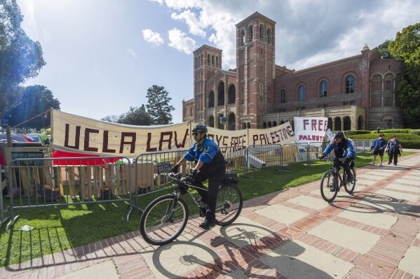 Die Polizei des UCLA-Campus radelt am Freitag, 26. April 2024, in Los Angeles um ein pro-palästinensisches Lager auf dem UCLA-Campus herum.  (AP Photo/Damian Dovarganes)