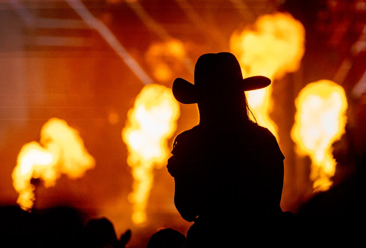 Silhouette einer Frau mit Cowboyhut vor einem pyrotechnischen Schauspiel 