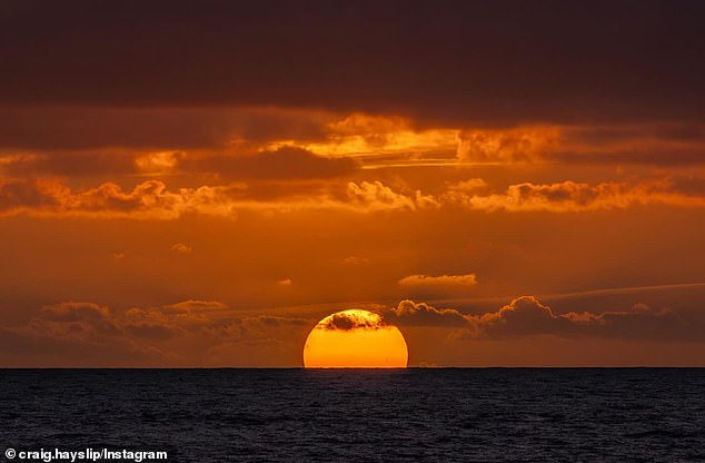 Auf dem ersten Foto, das Hayslip gepostet hat, war ein Teil der Sonne zu sehen, wie sie hinter dem Horizont unterging, während dunkelorangefarbene Wolken darüber schwebten