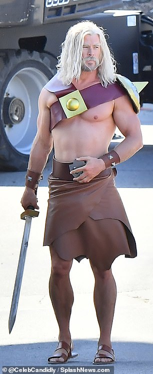 He was clad in a spikey shoulder sash, brown spiked wrist cuffs, a belted brown leather wrap skirt, and sandals