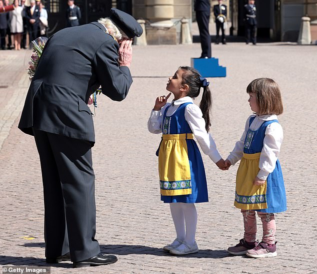 Dem König scheint es schwer zu fallen, zwei junge Mädchen in traditioneller Kleidung zu hören