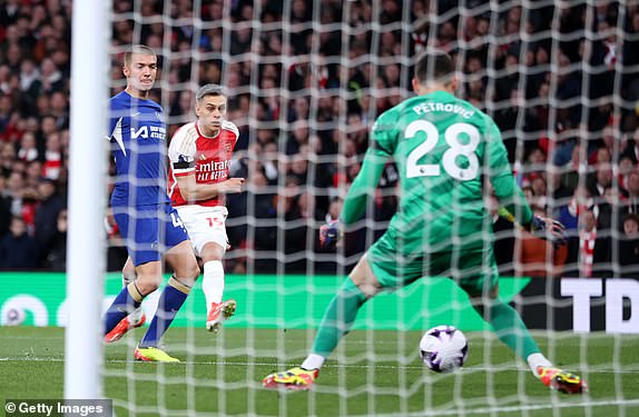 LONDON, ENGLAND - APRIL 23: Leandro Trossard of Arsenal scores his team's first goal past Djordje Petrovic of Chelsea during the Premier League match between Arsenal FC and Chelsea FC at Emirates Stadium on April 23, 2024 in London, England. (Photo by Alex Pantling/Getty Images)
