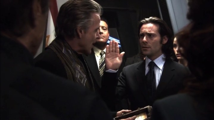 Gaius Baltar hebt seine Hand, als er in der Battlestar Galactica-Folge als Präsident vereidigt wird "Legen Sie Ihre Lasten ab, Teil 2"
