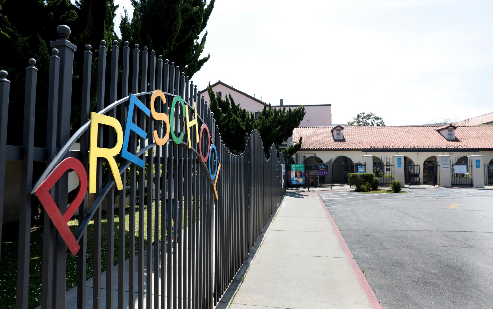 Ein Zaun mit einem Schild mit der Aufschrift "Vorschule," und Schulgebäude