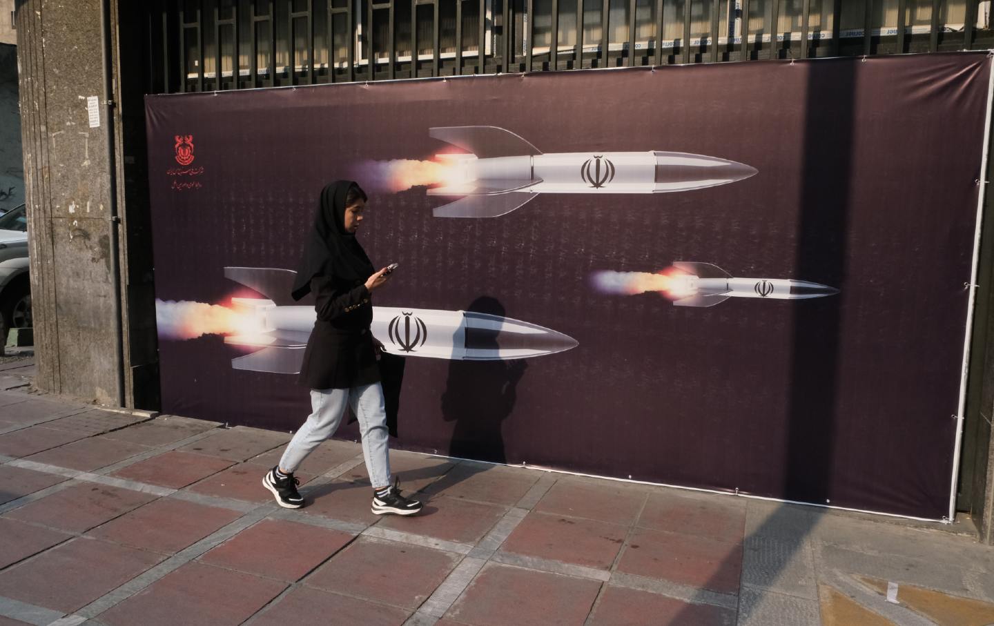 Frau geht an Foto iranischer Raketen vorbei
