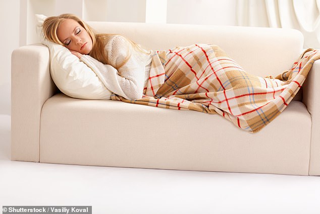 Eine Frau schläft auf einem Sofa unter einer Decke.  Wissenschaftler sagen, dass beschwerte Decken die Freisetzung von Wohlfühlchemikalien im Gehirn auslösen, das auf den Druck der Decke wie auf eine Umarmung oder ein Kuscheln reagiert (Archivbild)