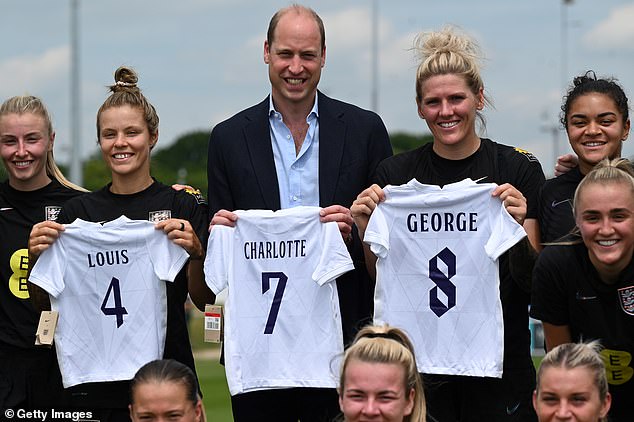 Prince William poses with England players including Rachel Daly (2nd L) and Millie Bright (2nd R) after receiving a gift of three England shirts, each bearing the name of one of his children, whilst visiting the England Women's football team at St. George's Park on June 15, 2022 in Burton upon Trent