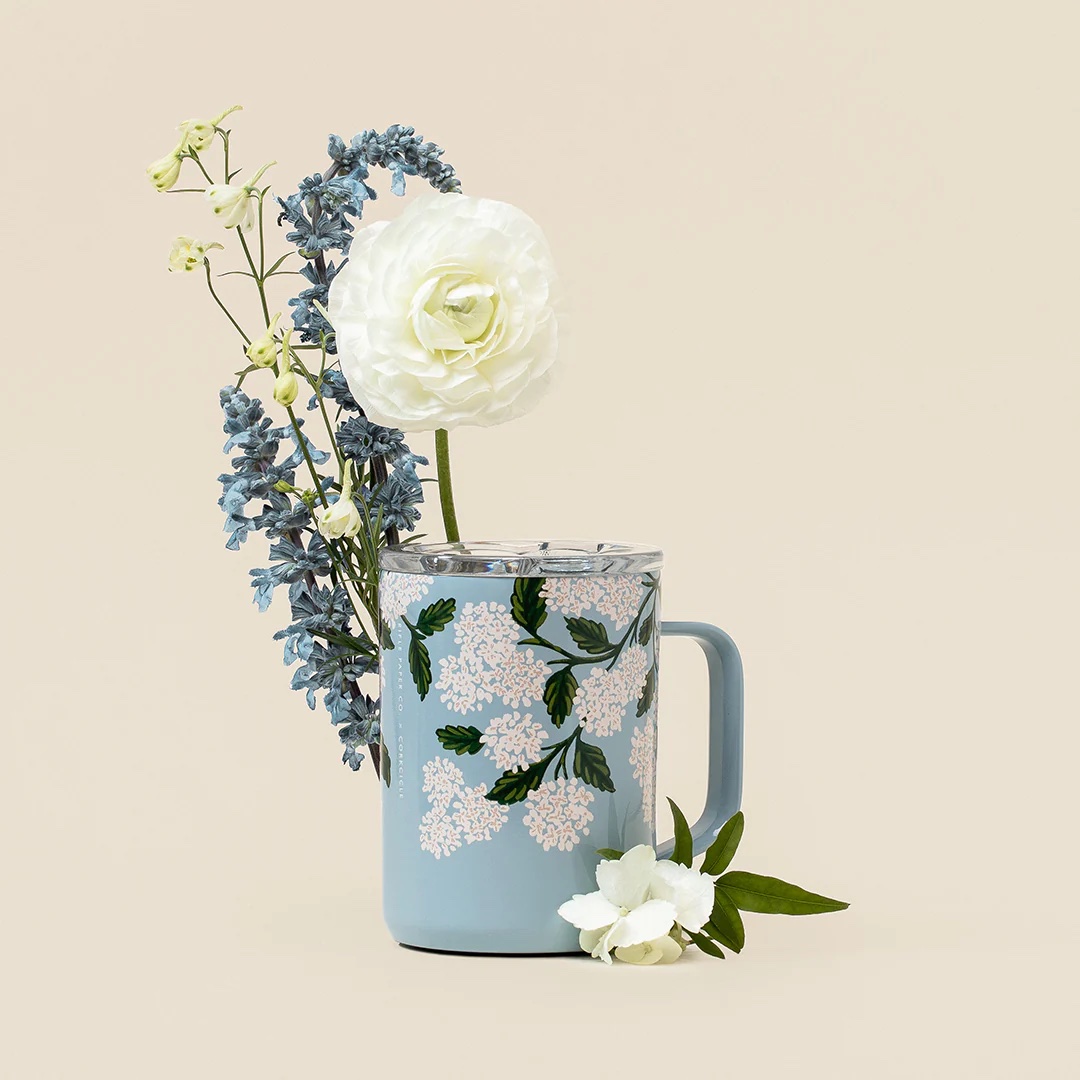 Eine Kaffeetasse, umgeben von Blumen