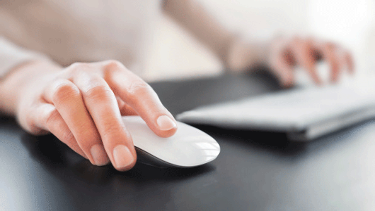 Frauenhand auf einer Computermaus und Tastatur