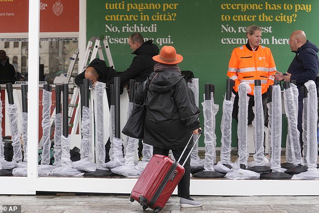Oben bereiten Arbeiter die Kurtaxenkasse vor dem Hauptbahnhof in Venedig vor