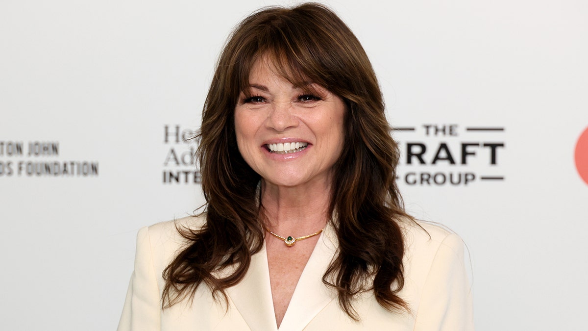 Valerie Bertinelli lächelt in einem cremefarbenen Anzug mit weißem Hintergrund
