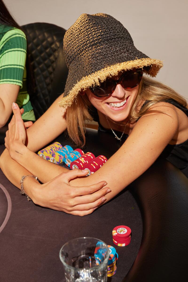 Die Künstlerin Ava McDonough, mit Sonnenbrille und Strohhut, hält ihre Pokerchips fest in den Armen.