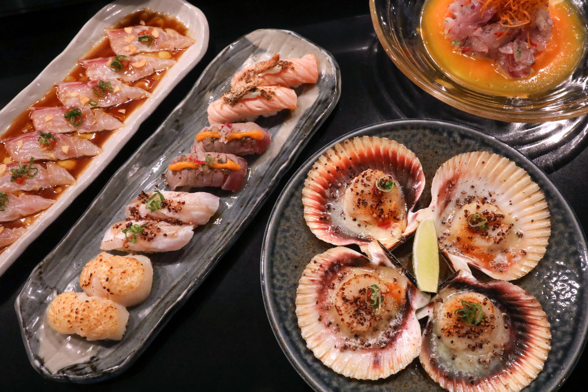 Vier Gerichte, darunter Sushi und offene Jakobsmuscheln