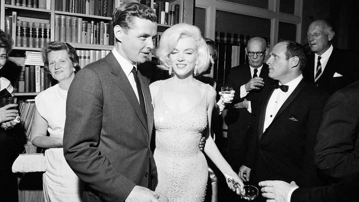 Marilyn Monroe geht neben einem Mann im Anzug