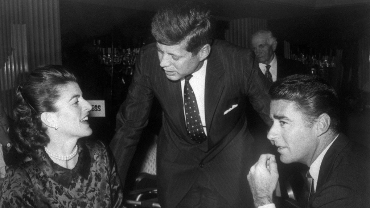 John F. Kennedy spricht mit seiner Schwester Patricia, während Peter Lawford zuhört