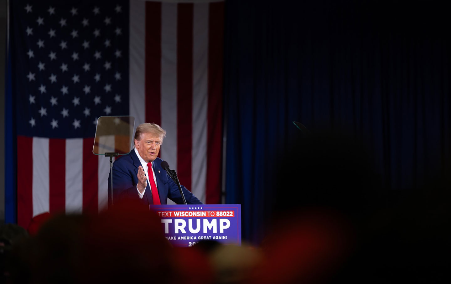 Donald Trump auf einem Podium vor einer amerikanischen Flagge.