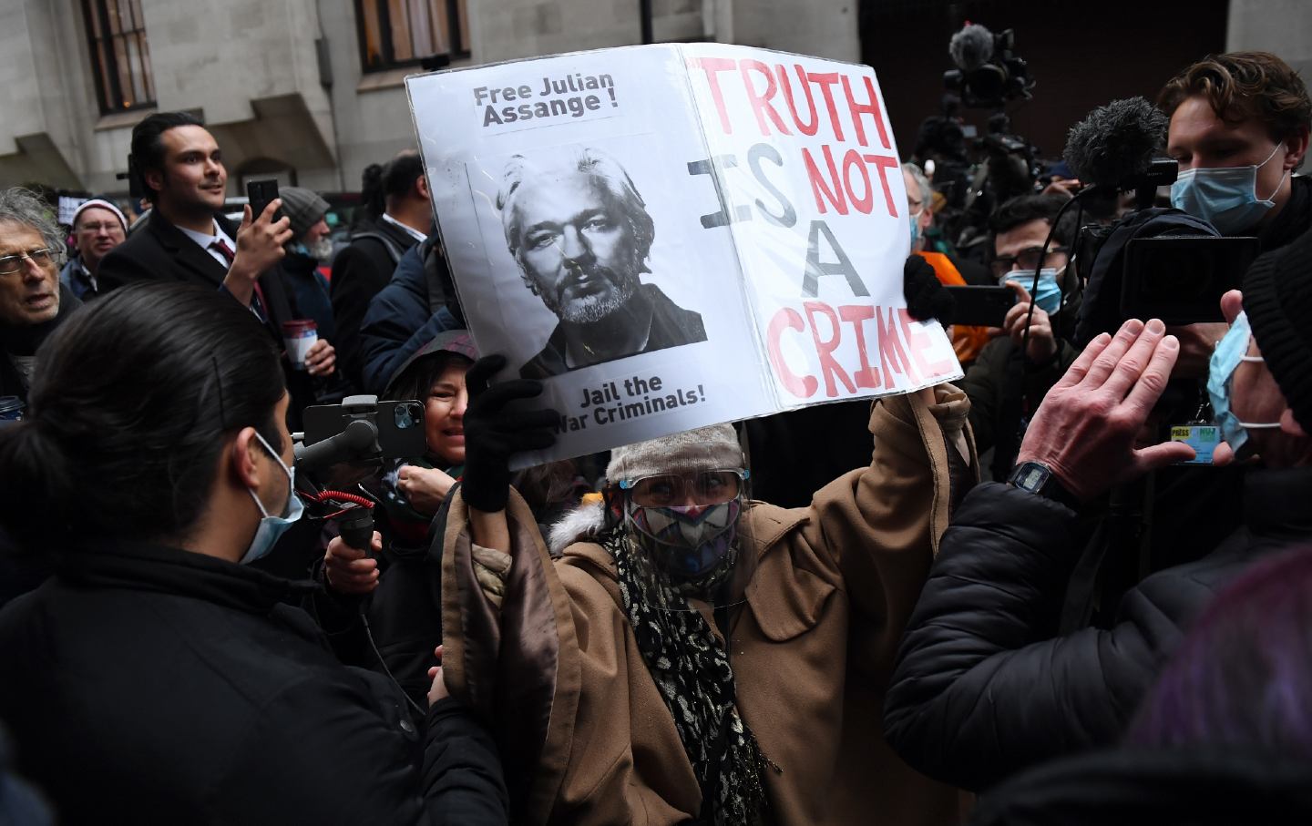 Julian Assange-Anhänger feiern draußen, einer hält ein Schild mit der Aufschrift „ 
