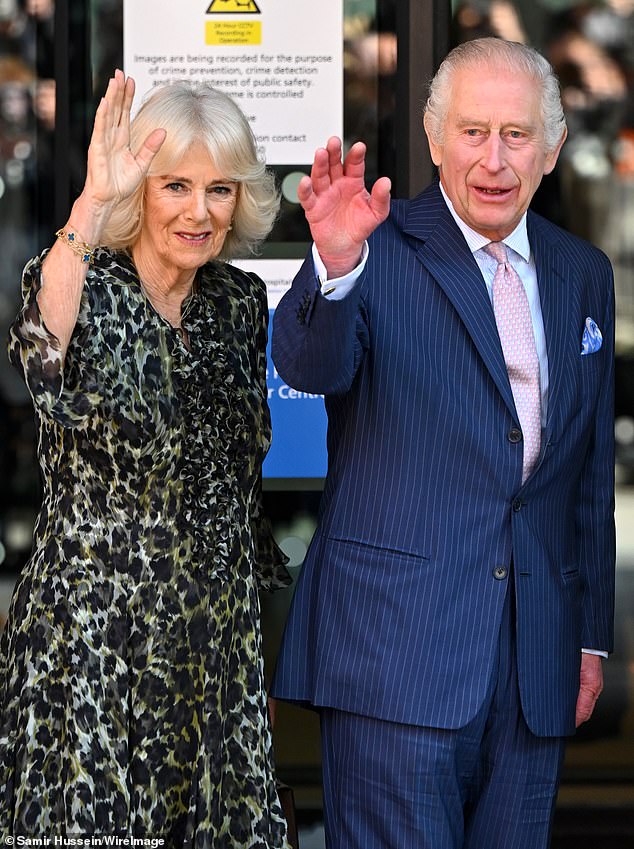 King Charles today marked his return to public duties wearing his famed pink and blue T-rex tie (His Majesty is pictured with Queen Camilla at the University College Hospital Macmillan Cancer Centre this morning)