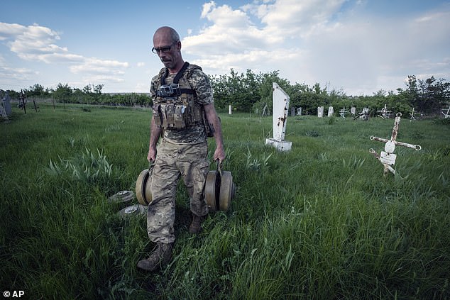 A Ukrainian sapper carries mines after he cleared a cemetery the site of heavy battles with Russian troops in the village of Krasnopillya, Ukraine, May 2