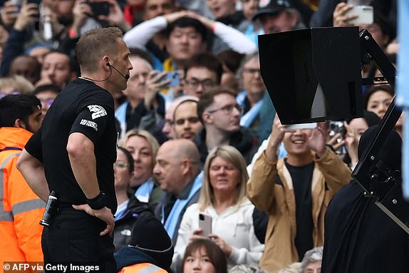 English referee Craig Pawson consults the pitch-side monitor before granting a second penalty to City during the English Premier League football match between Manchester City and Wolverhampton Wanderers at the Etihad Stadium in Manchester, north west England, on May 4, 2024. (Photo by Darren Staples / AFP) / RESTRICTED TO EDITORIAL USE. No use with unauthorized audio, video, data, fixture lists, club/league logos or 'live' services. Online in-match use limited to 120 images. An additional 40 images may be used in extra time. No video emulation. Social media in-match use limited to 120 images. An additional 40 images may be used in extra time. No use in betting publications, games or single club/league/player publications. /  (Photo by DARREN STAPLES/AFP via Getty Images)