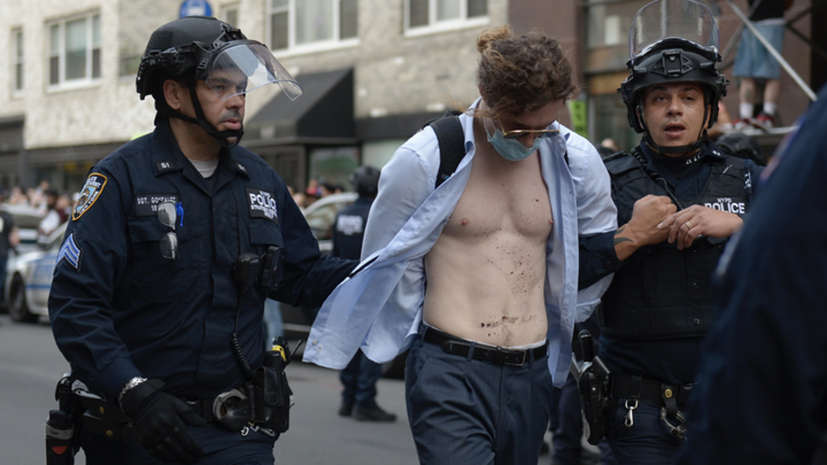 Ein Mann mit offenem Hemd wird von der Polizei festgenommen