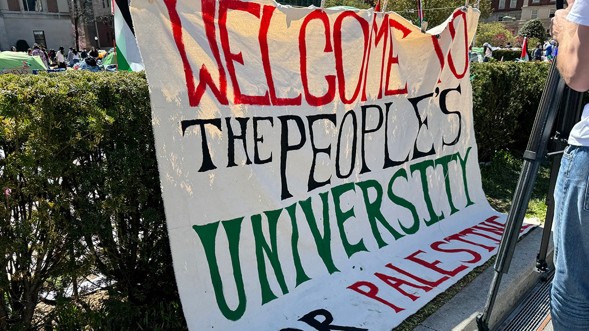 Auf einem Schild steht: "Willkommen an der Volksuniversität"