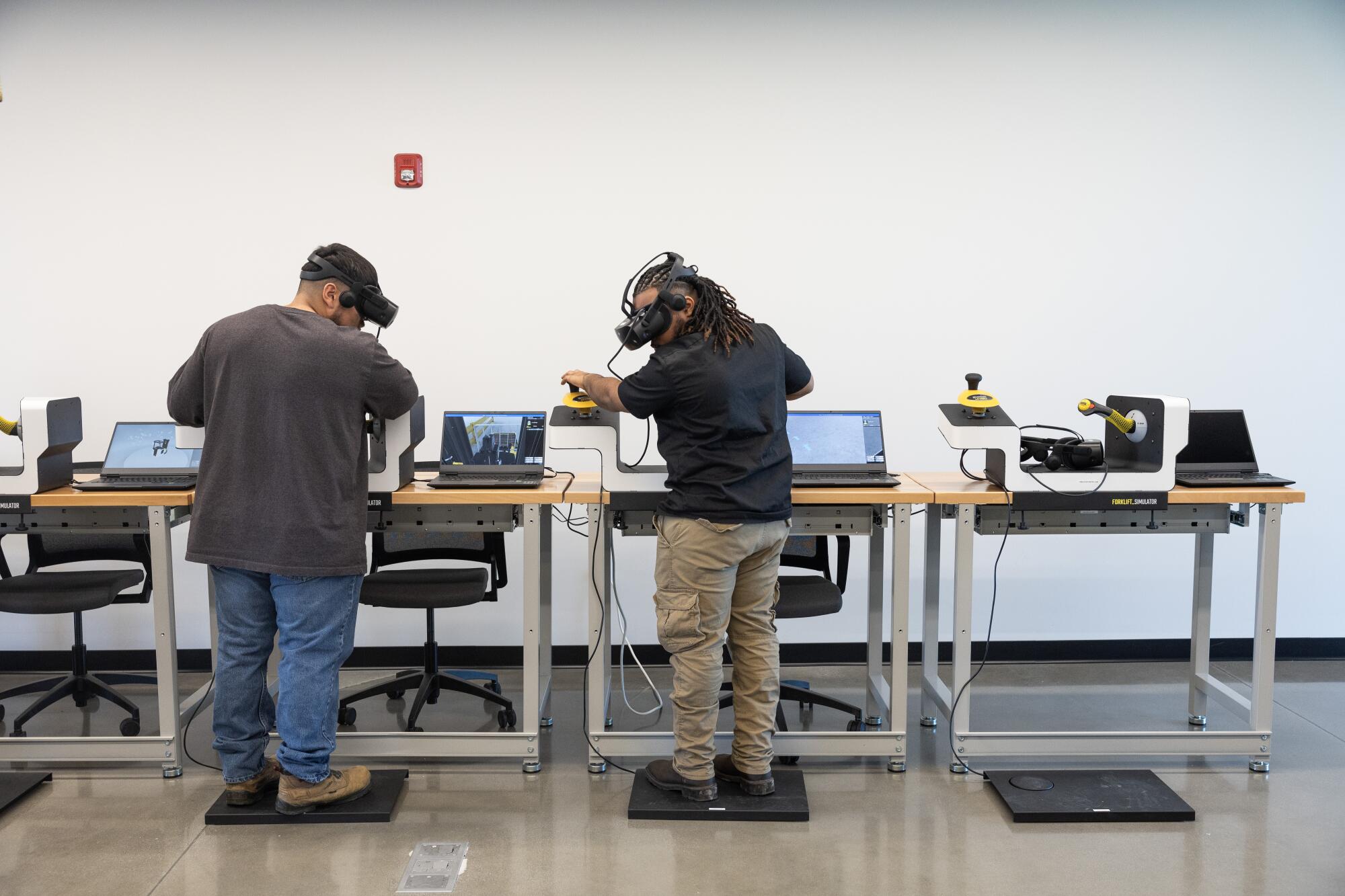 Zwei Männer tragen VR-Headsets, die den Gabelstaplerbetrieb simulieren.  