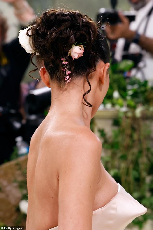 Das dunkelbraune Haar der Gründerin von Kylie Cosmetics war zu einer straffen Hochsteckfrisur zurückgebunden und ihre federnden Locken waren mit frischen Blumen festgesteckt