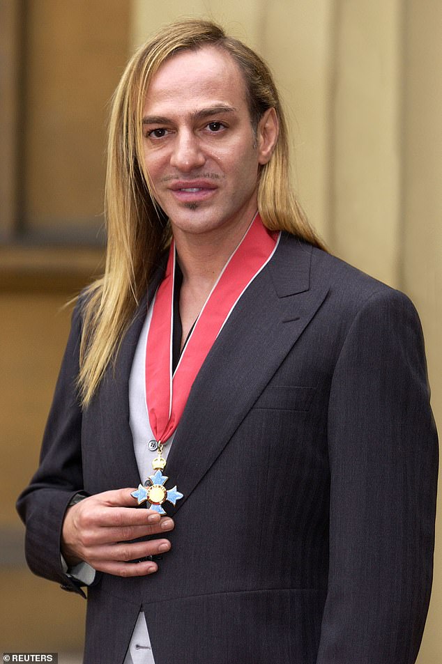 John Galliano poses for photographs after receiving an CBE from Queen Elizabeth II at Buckingham Palace on November 27, 2001
