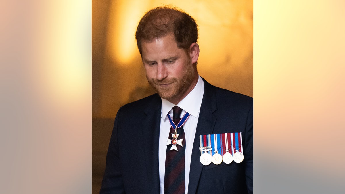 Prinz Harry schaut nach unten, während er einen Anzug mit Medaillen trägt