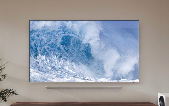 Der Samsung QN700B QLED 8K-Fernseher mit einer Welle auf dem Bildschirm, während er an der Wand montiert ist.