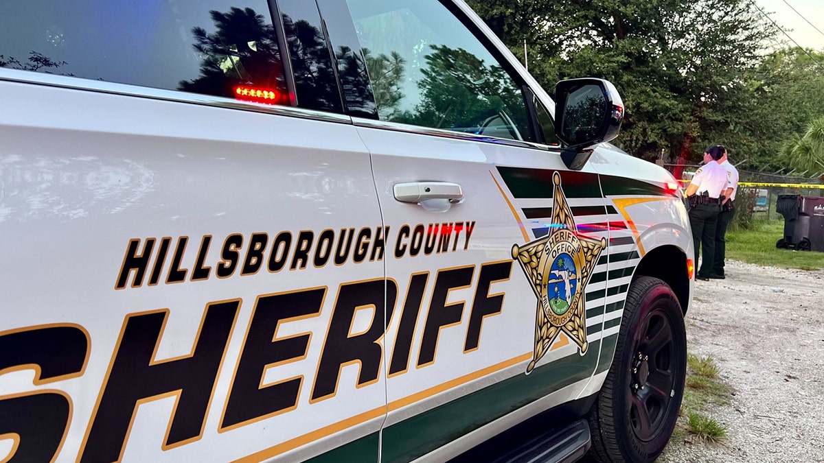Sheriff Cruiser aus Hillsborough County und zwei Beamte stehen am Absperrband der Polizei