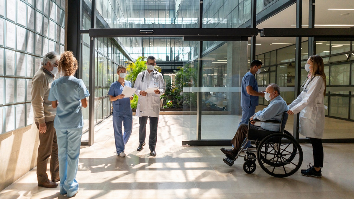 Menschen und Ärzte, die durch ein Krankenhaus laufen