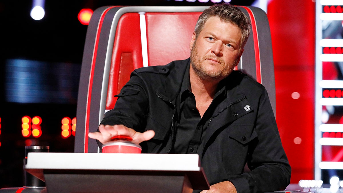 Blake Shelton in einer schwarzen Jacke drückt seinen Knopf, um seinen Stuhl bei „The Voice“ umzuschalten.