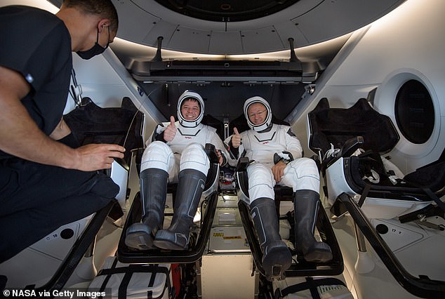 Die NASA-Astronauten Bob Behnken (links) und Doug Hurley (rechts) zeigen in der Dragon-Kapsel einen Daumen nach oben, während ein Flugarzt ihre Vitalwerte überprüft.  Das Team kehrte nach einer zweimonatigen Mission in der Internationalen Raumstation zur Erde zurück