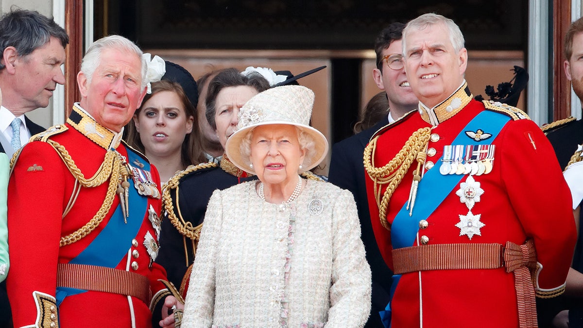 Queen Elizabeth standing on the palace balcony standing in between the former Prince Charles and Prince Andrew
