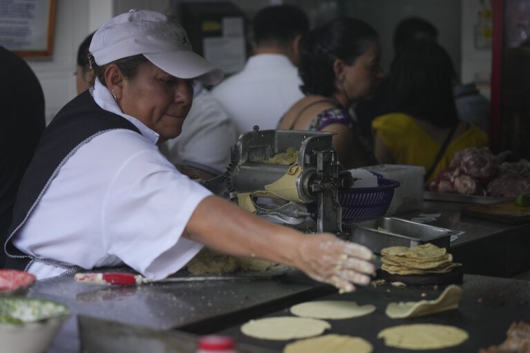 Ein Mitarbeiter wirft am Mittwoch, den 15. Mai 2024, am Taco-Stand Tacos El Califa de León in Mexiko-Stadt eine Tortilla auf eine Grillplatte. Tacos El Califa de León ist der erste Taco-Stand überhaupt, der vom französischen Restaurantführer einen Michelin-Stern erhalten hat .  (AP Photo/Fernando Llano)