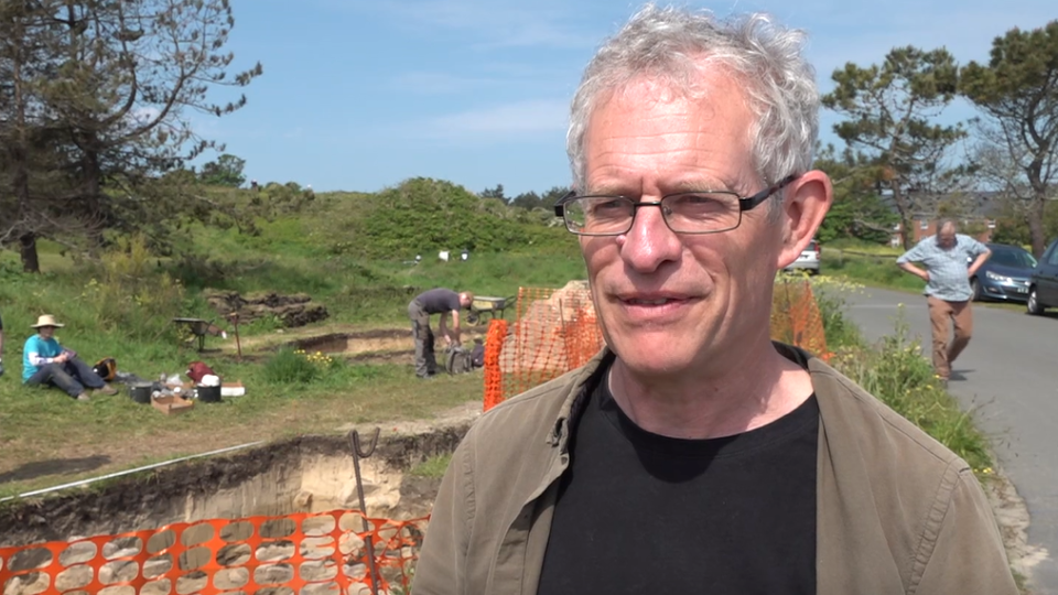 Der US-Archäologe Phil de Jersey steht vor der Ausgrabungsstätte in Guernsey