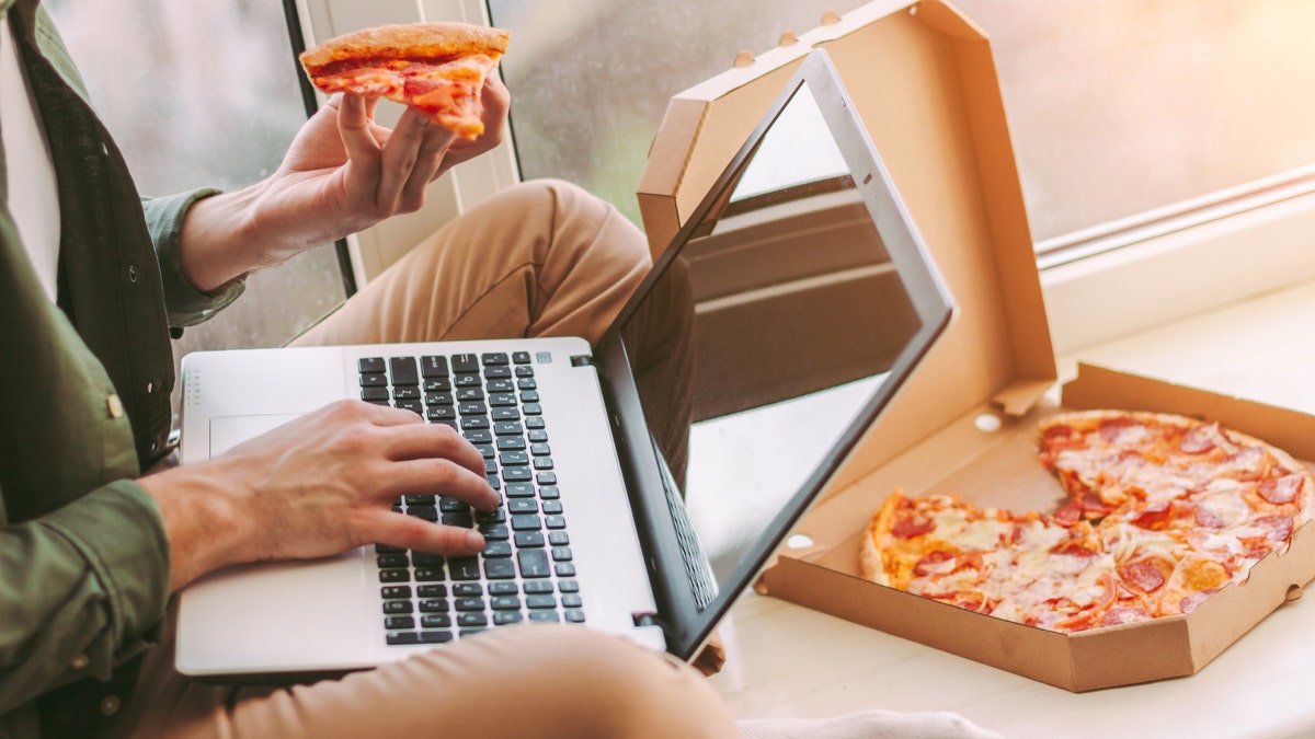 Mann isst Pizza während der Arbeit