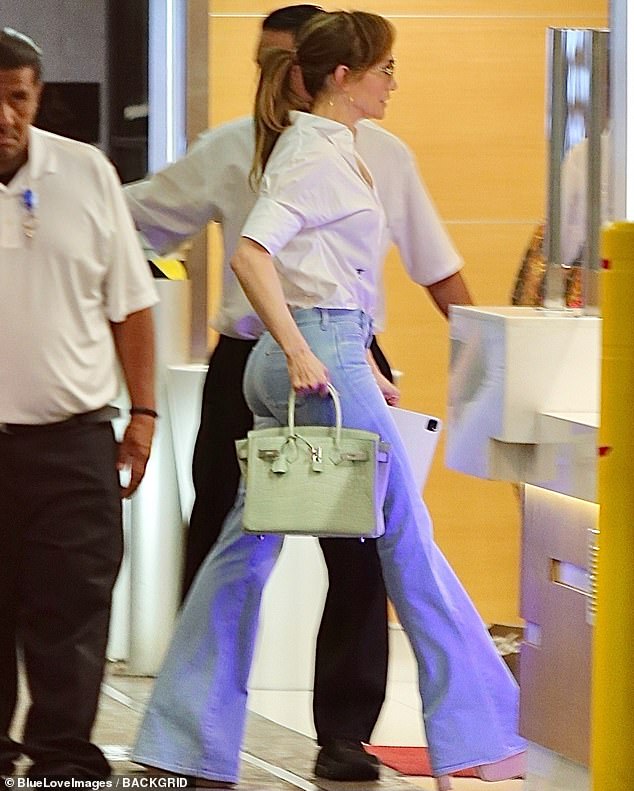 Lopez - who is 'over' trying to salvage her doomed marriage - put on a stylish display wearing a pair of light blue, denim jeans with a flared hem and tucked in a white blouse into the waist of the pants
